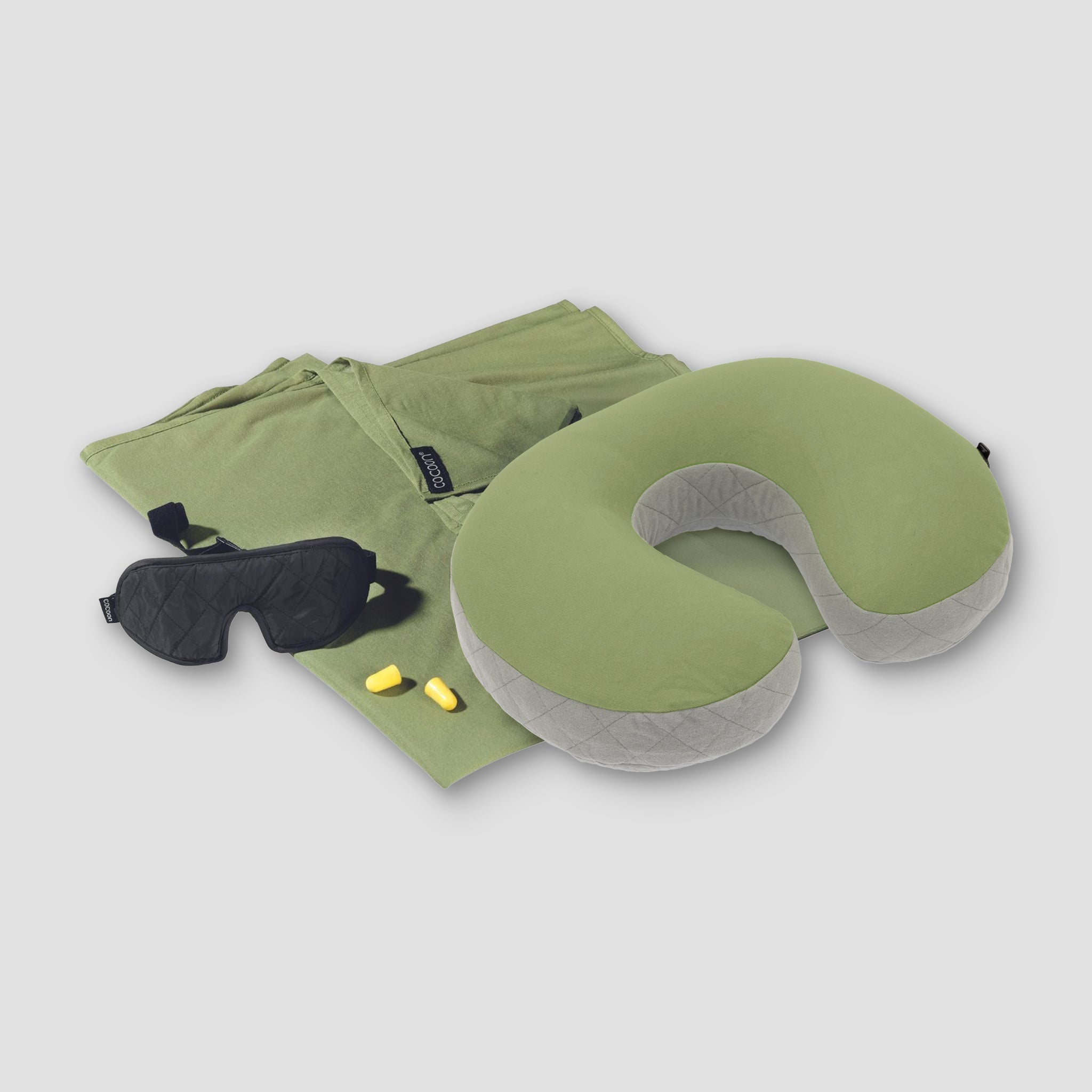 Green travel pillow, eye mask, and earplugs on a white background