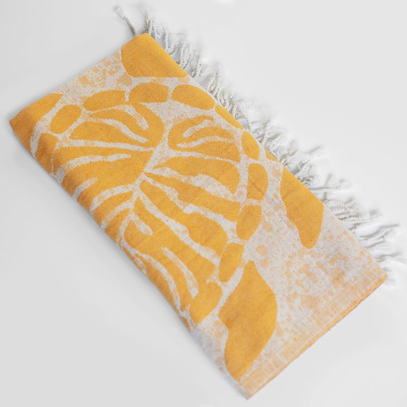 Yellow and white patterned towel with frayed edges on a light gray background