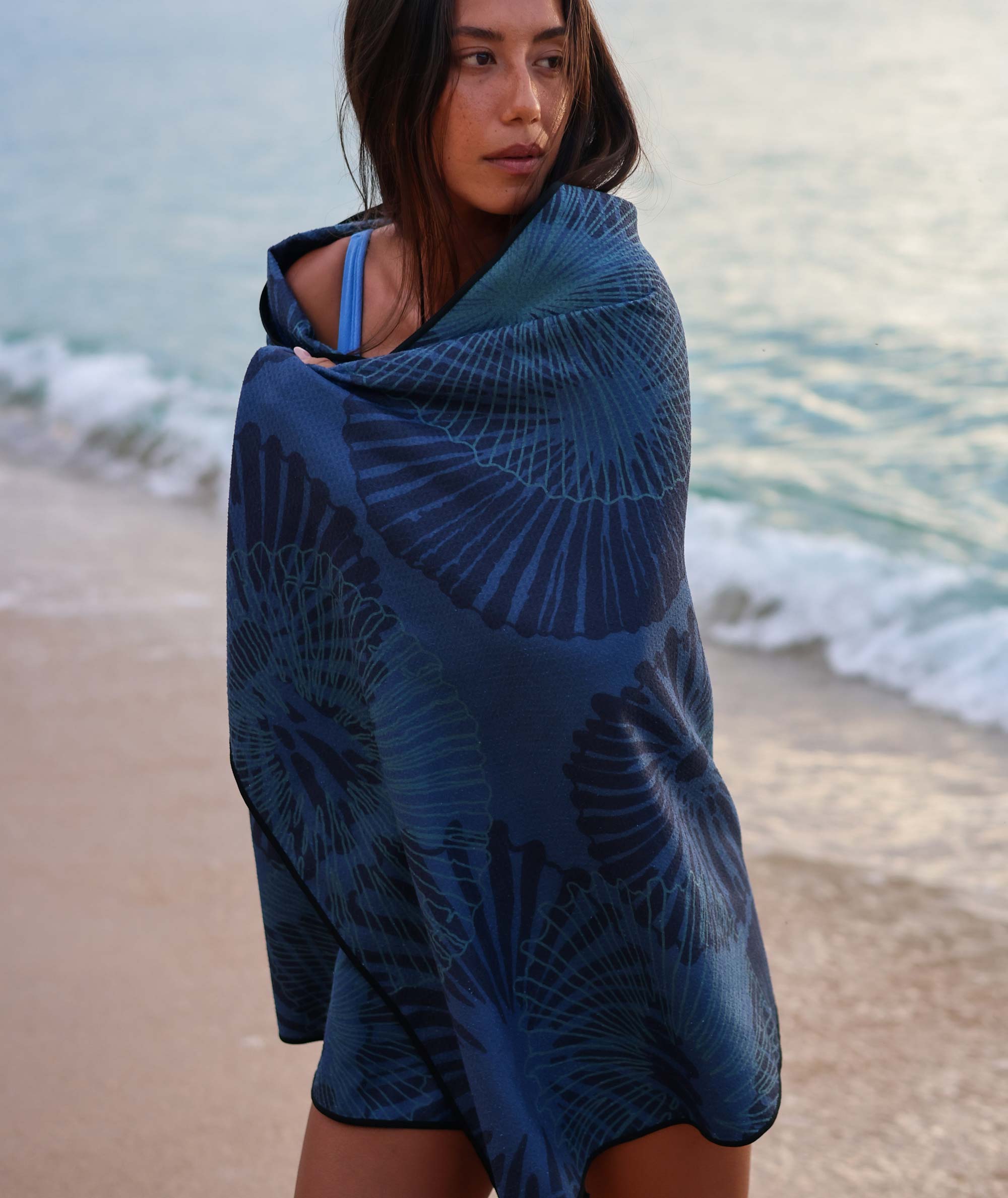Woman wrapped in a blue patterned towel on a beach