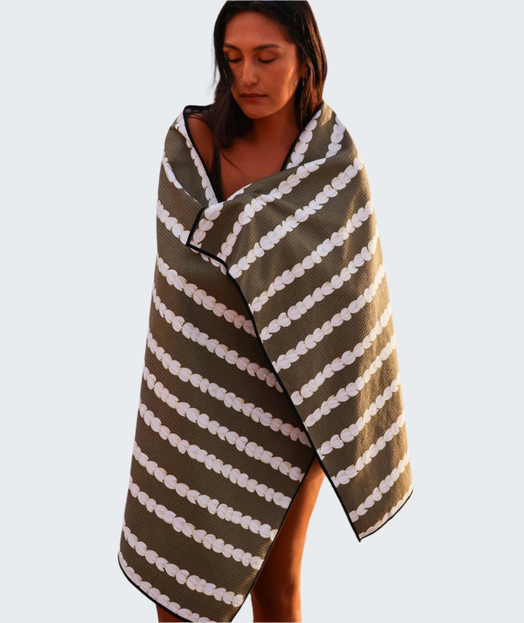 Woman wrapped in a brown and white striped towel by the water