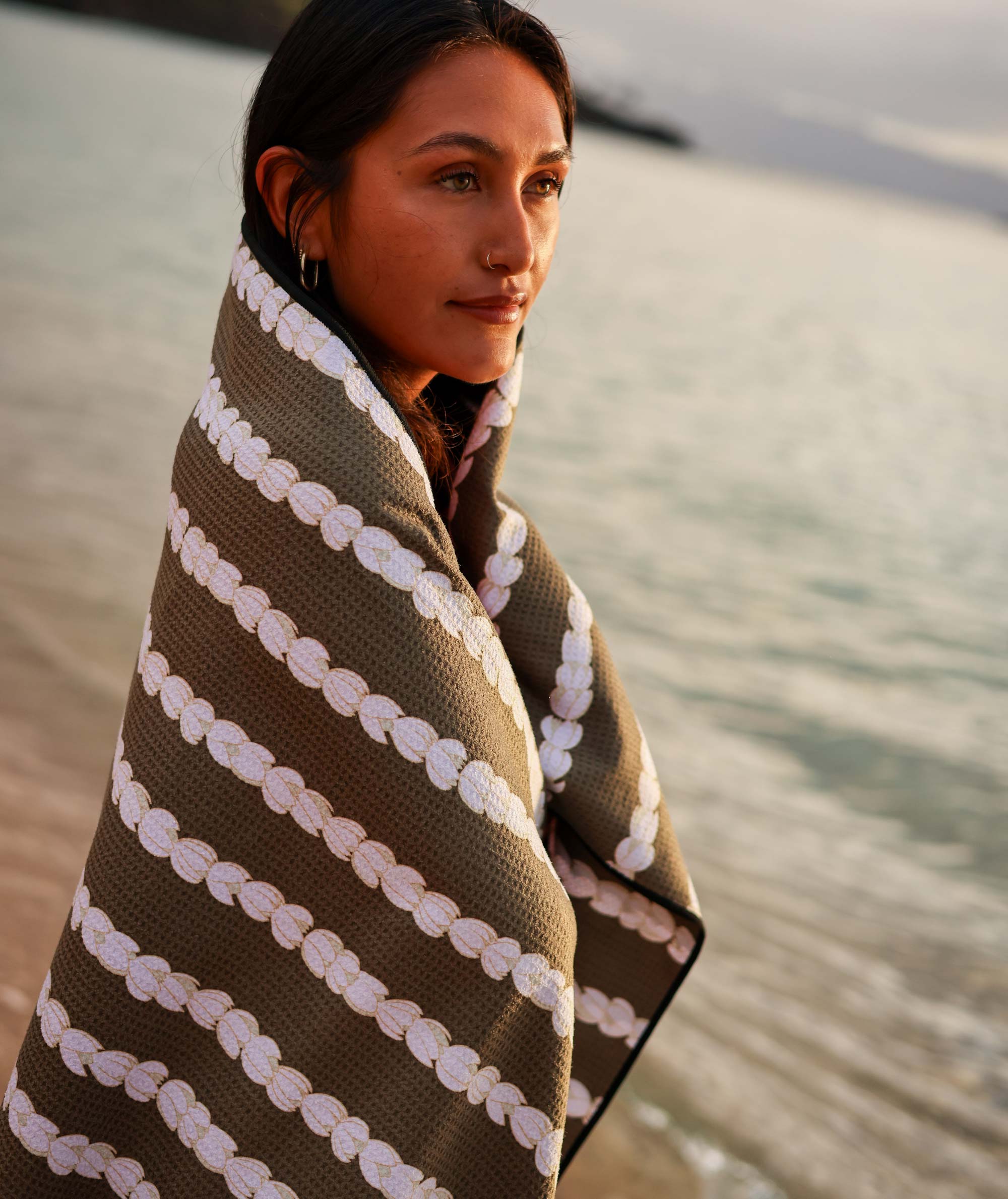 Woman wrapped in a patterned towel by the water