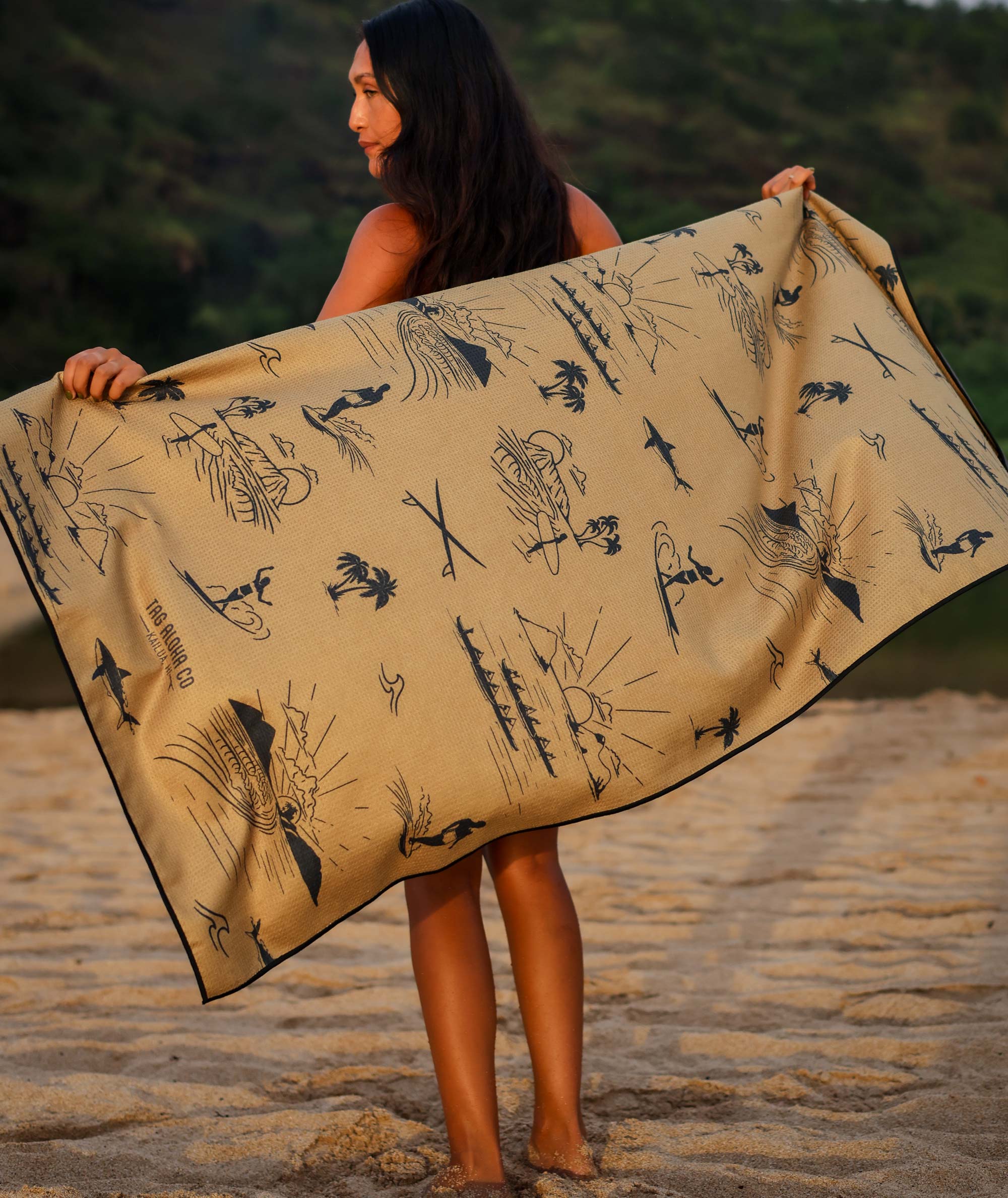 Woman holding a beige towel with black patterns on a beach