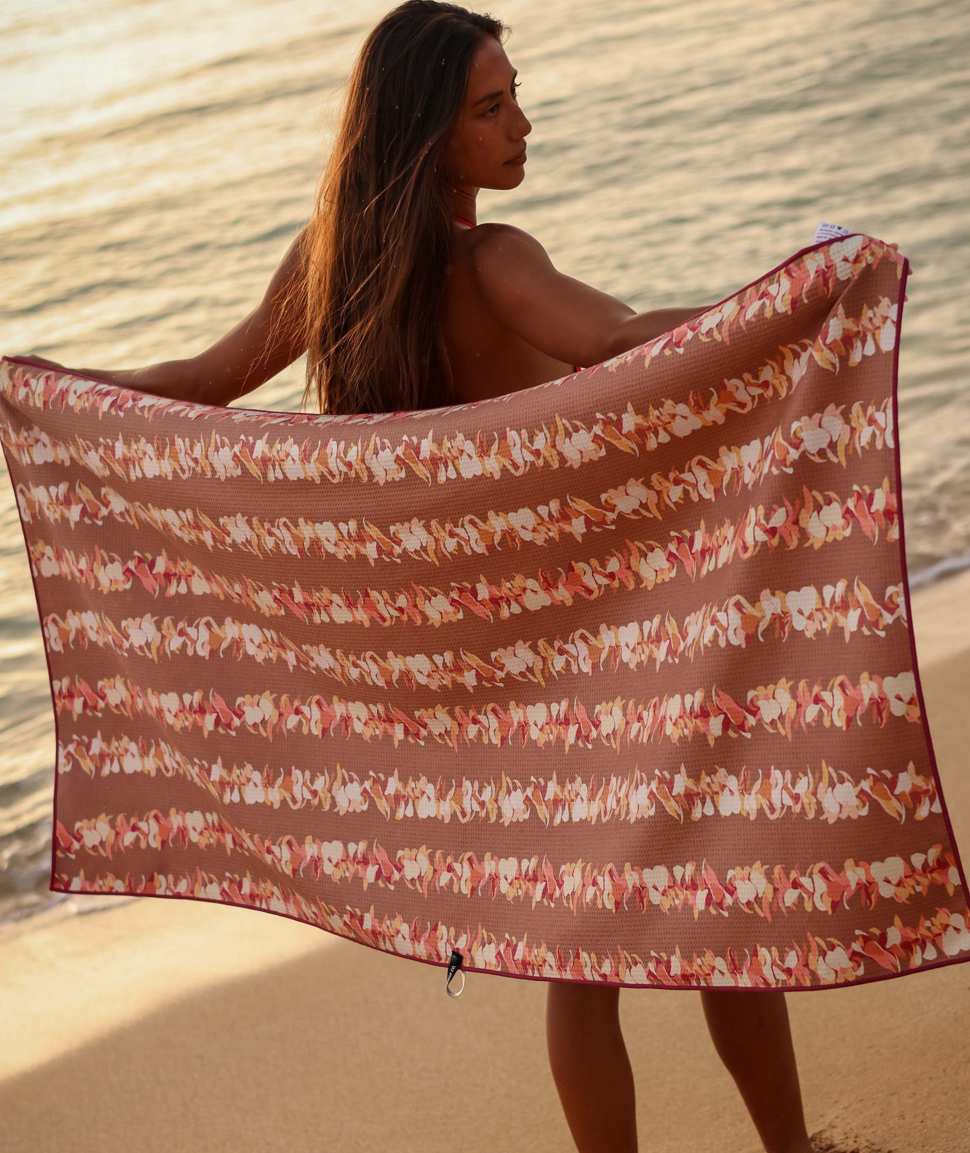 Woman holding a patterned towel on a beach