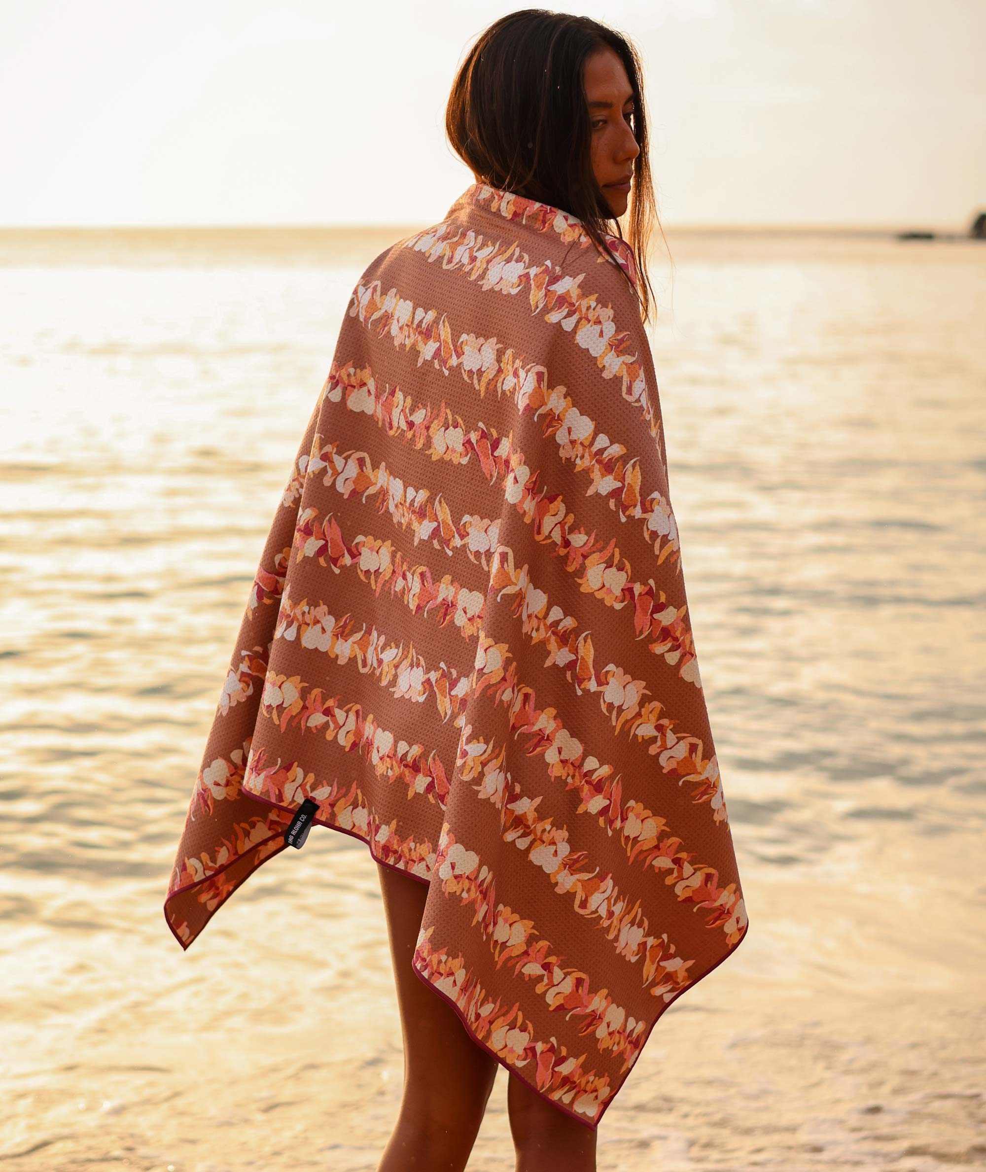Woman standing on a beach wearing a patterned towel