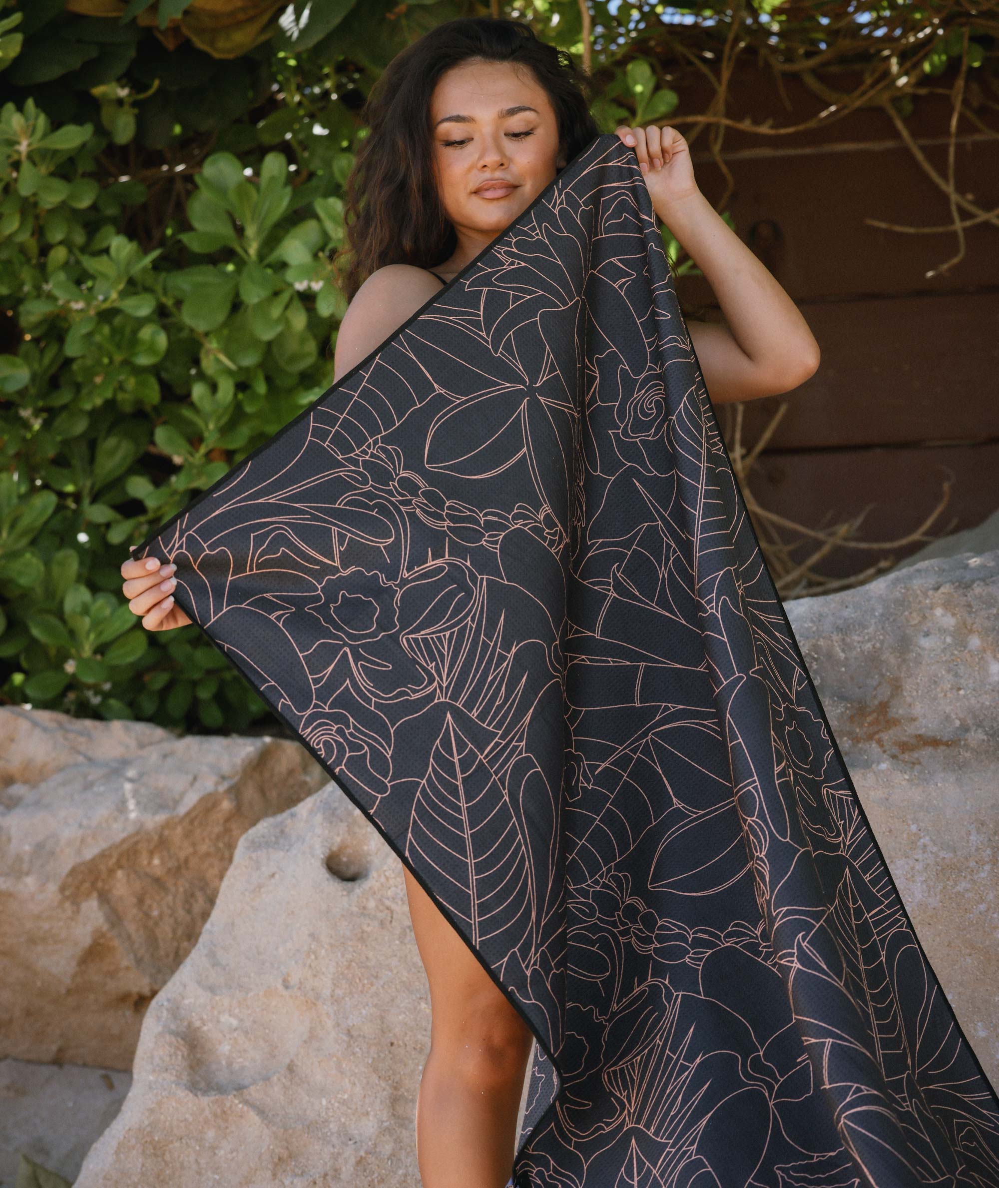 Woman holding a dark towel with floral patterns outdoors