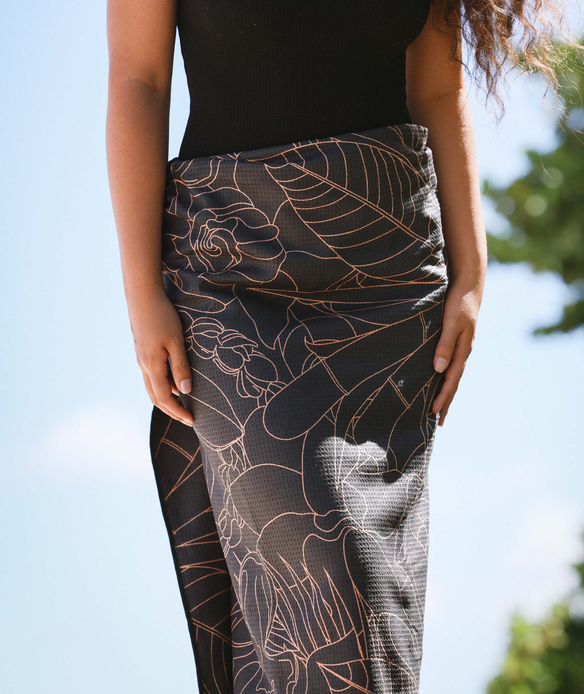 Person wearing black leggings with floral patterns against a blurred natural background