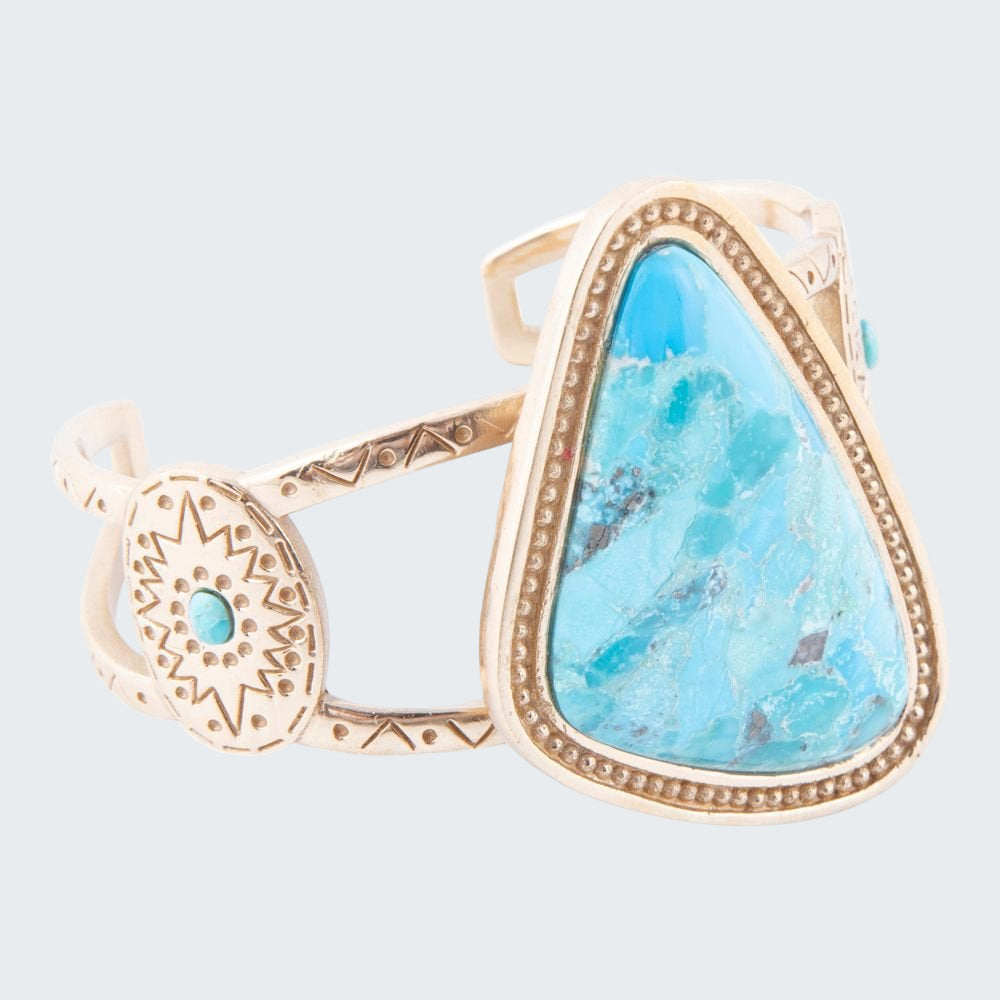 Gold ring with a large turquoise stone on a white background