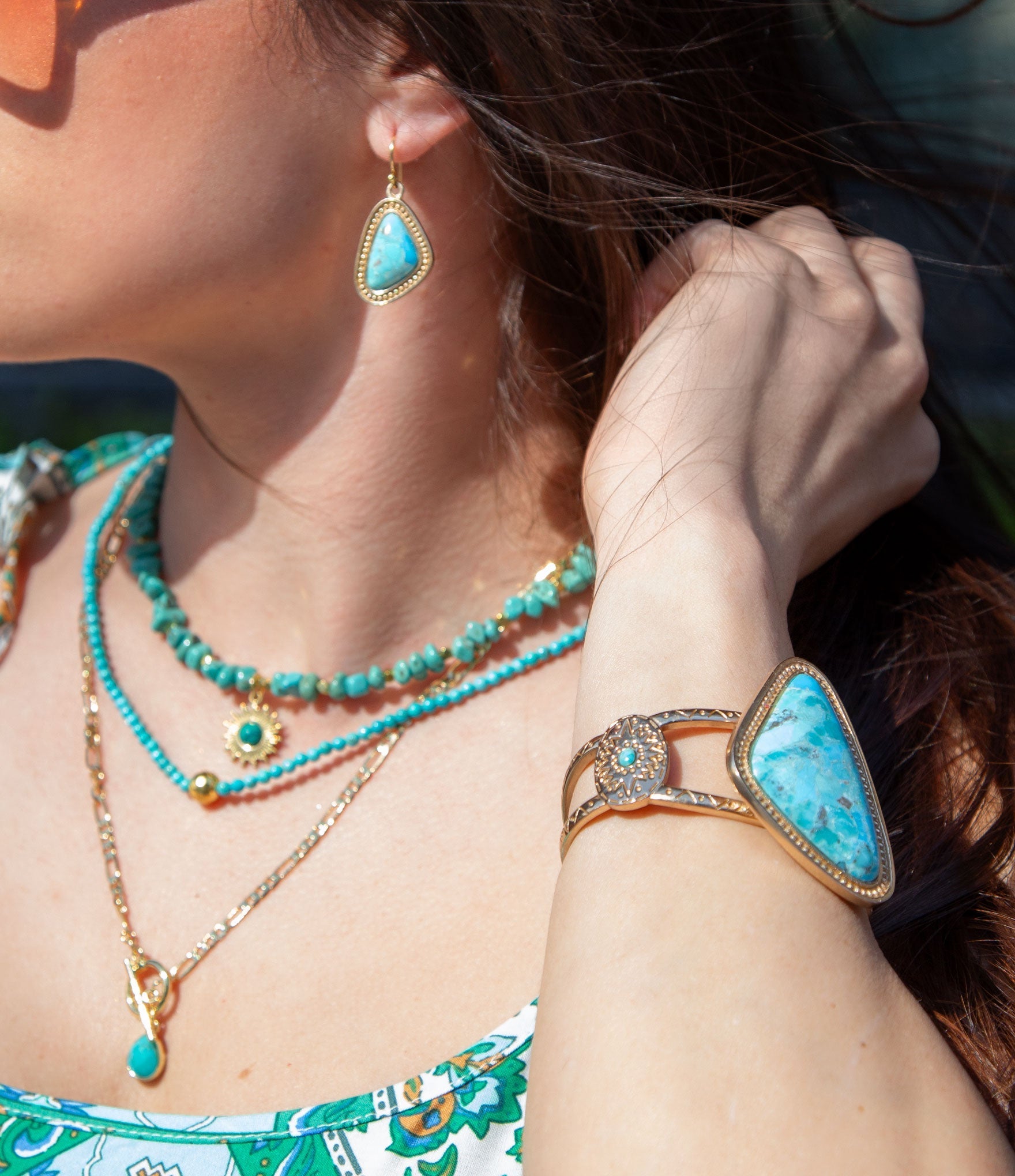 Close-up of a person wearing turquoise jewelry including earrings, necklace, and bracelet.