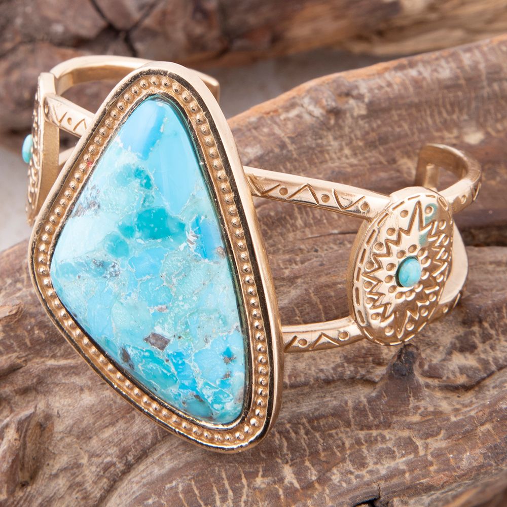 Gold ring with turquoise stone on a wooden surface