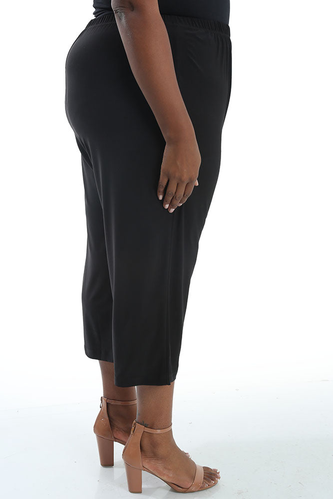 Person wearing black pants and tan high-heeled sandals on a white background