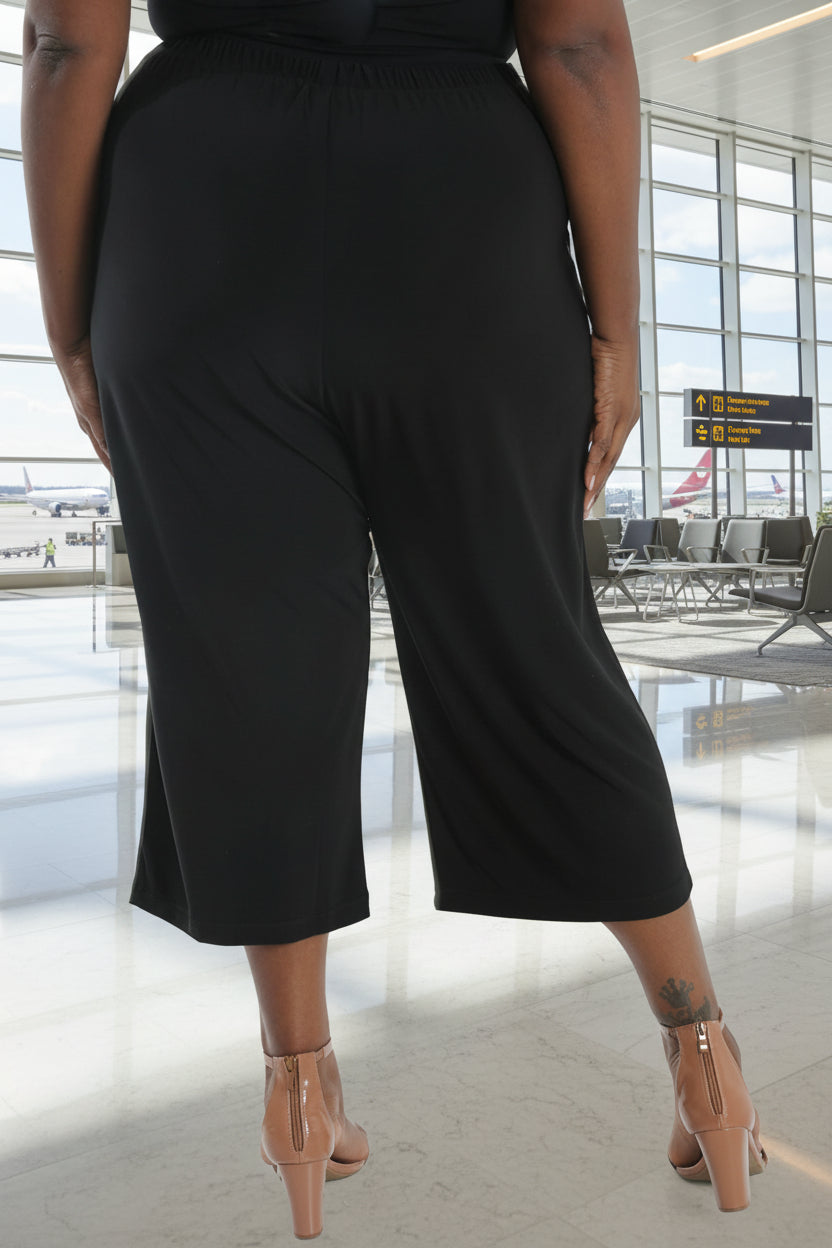 Person wearing black wide-leg pants on a white background