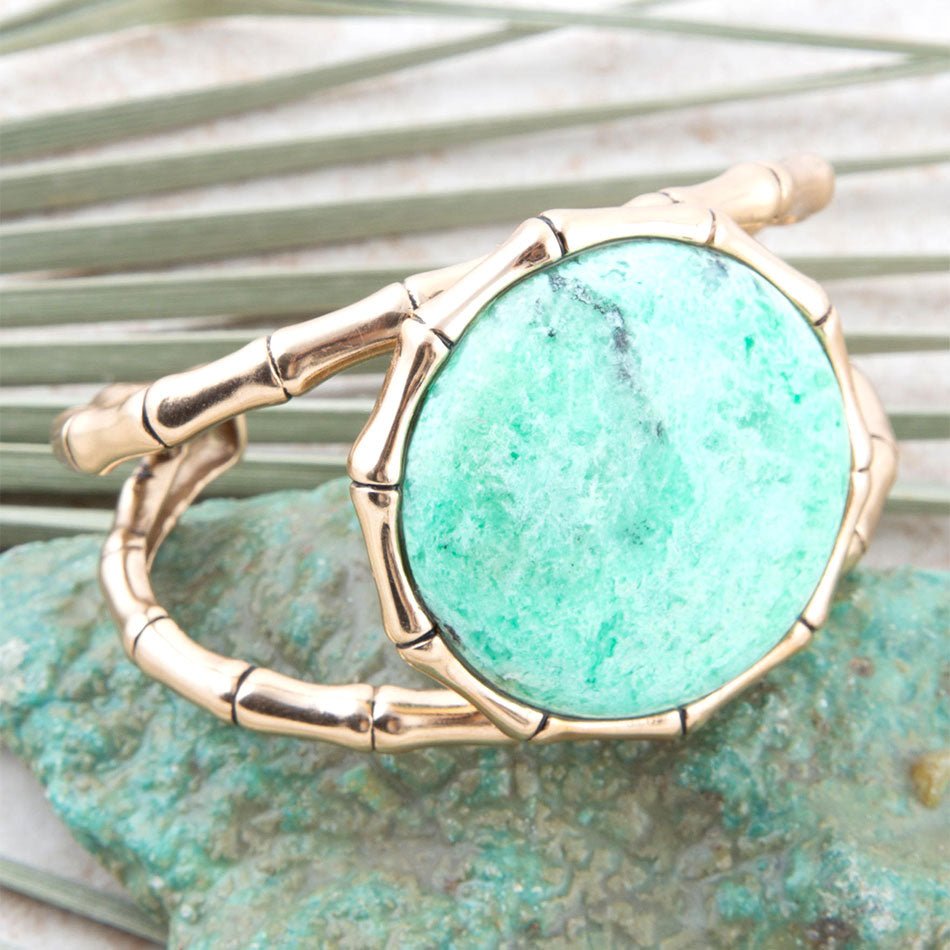 Gold ring with a turquoise stone on a textured green background