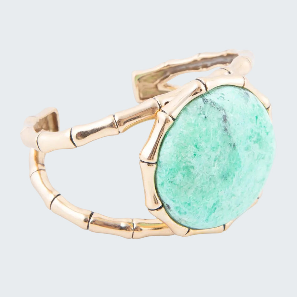 Gold ring with a large green stone on a white background