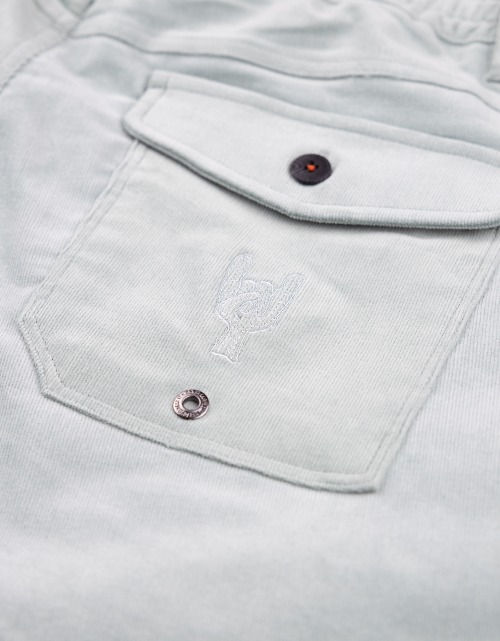 Close-up of a light gray corduroy shirt with a pocket and buttons.