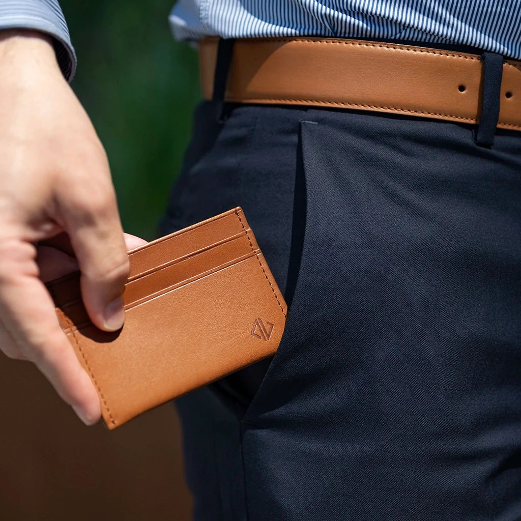 Person holding a brown leather cardholder with a blurred background