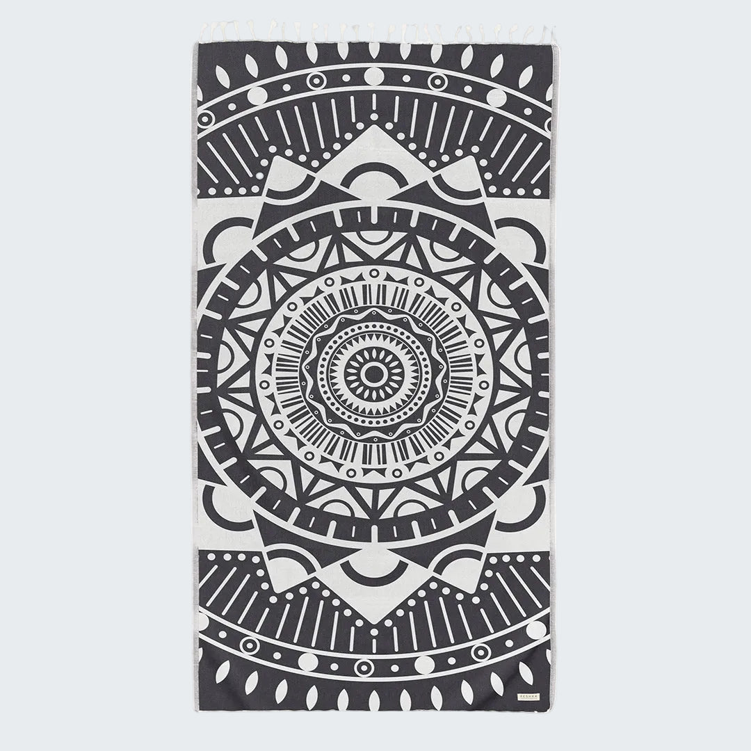 Black and white mandala design on a folded towel against a white background