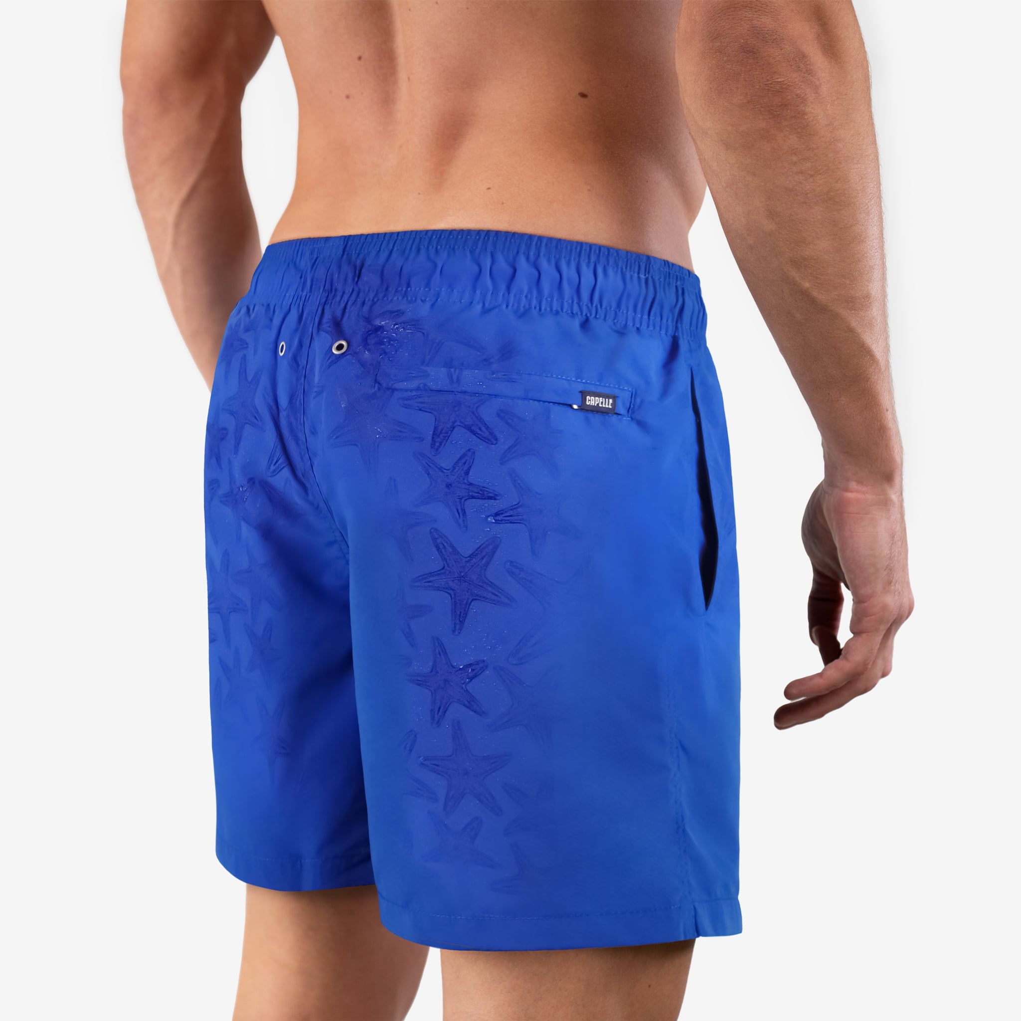Blue swim shorts with starfish pattern worn by a person on a white background