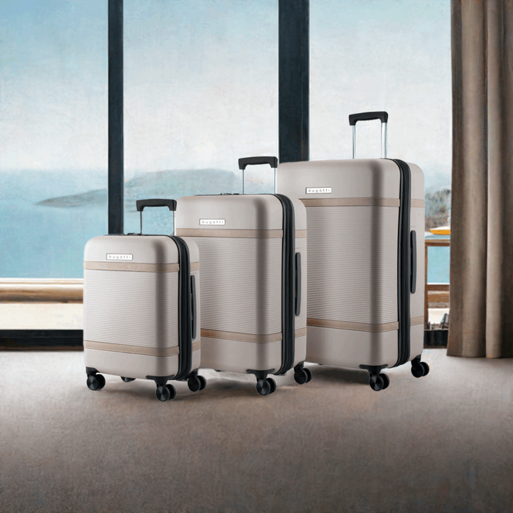 Set of three beige suitcases with black wheels in front of a window with a view of water.