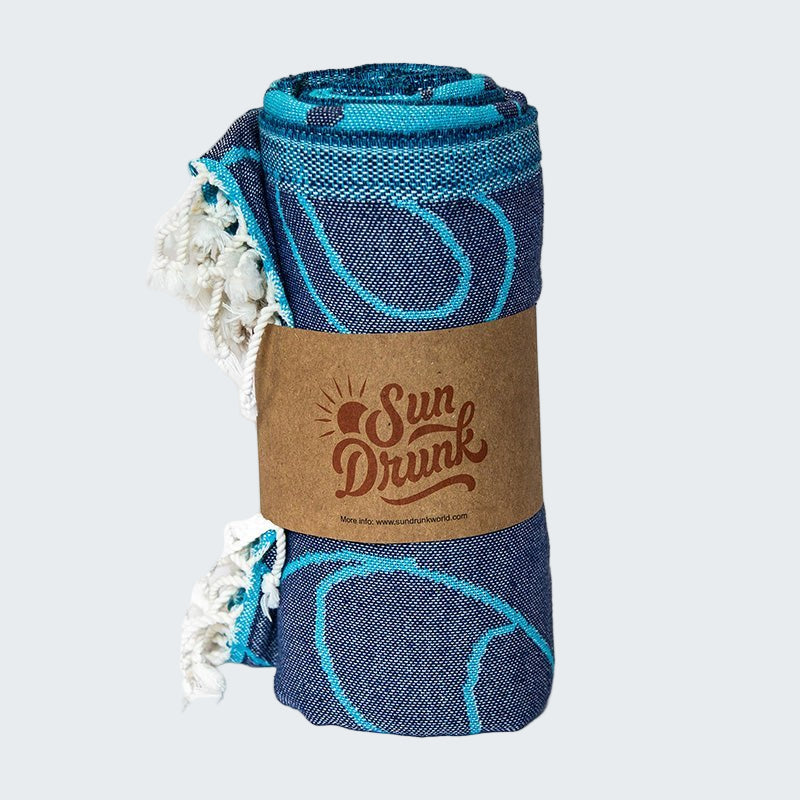 Rolled-up blue towel with white tassels and a brown label on a white background