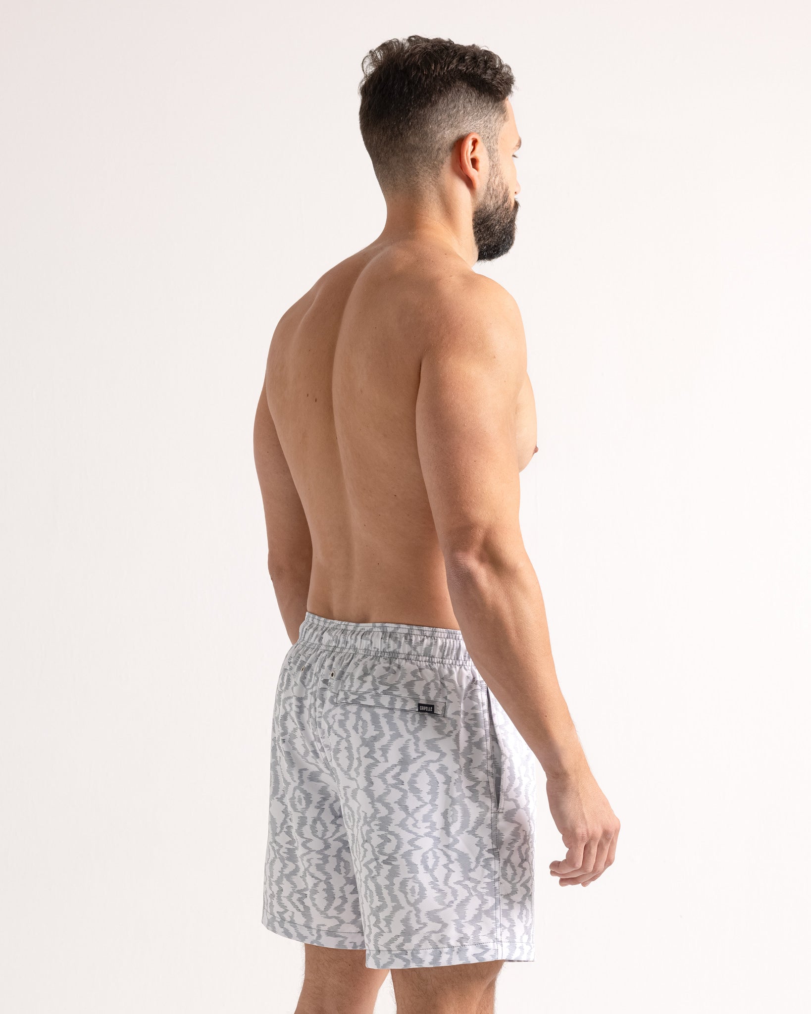 Man wearing gray patterned swim shorts on a white background