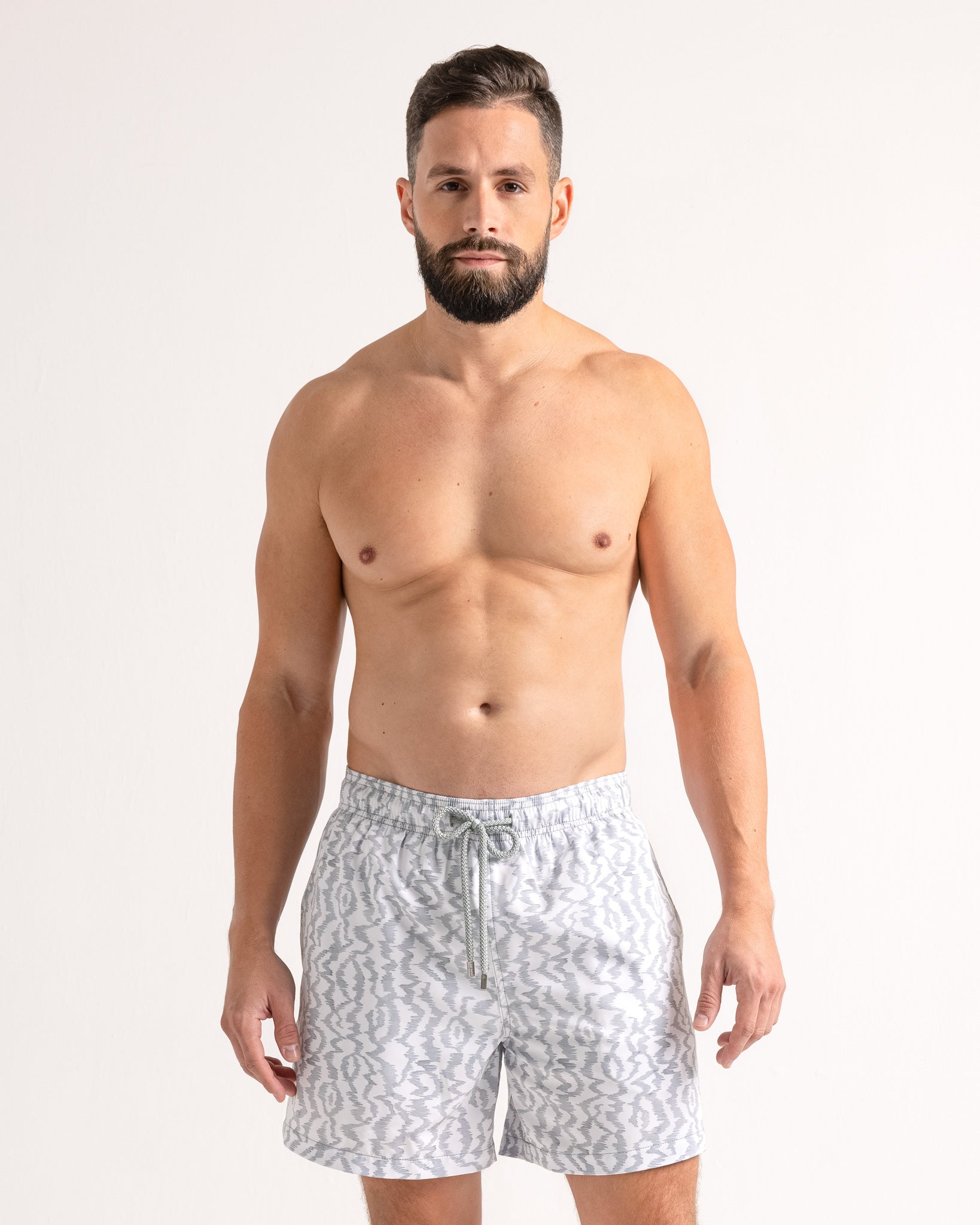 Man wearing white patterned shorts on a plain background