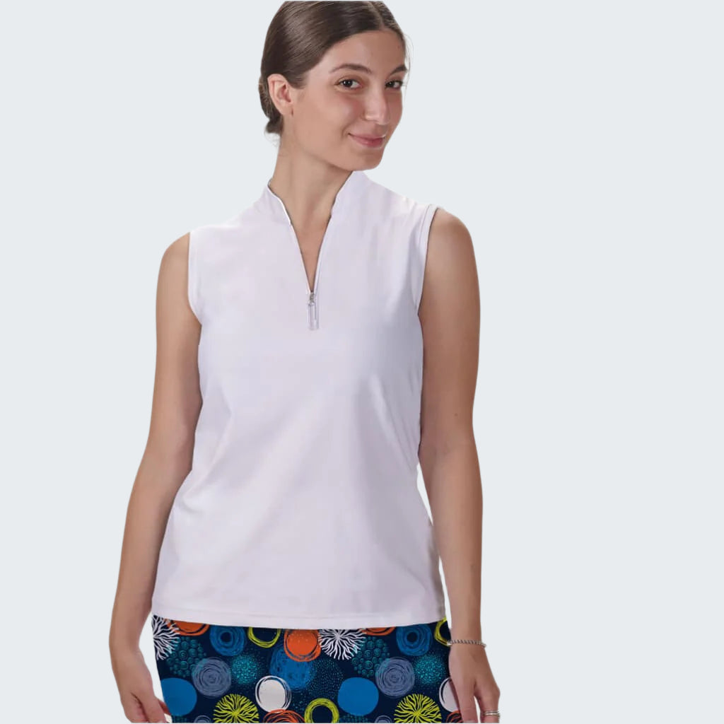 Woman wearing a white sleeveless top with colorful polka dot shorts on a plain background