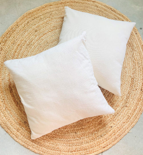Two white pillows on a woven mat