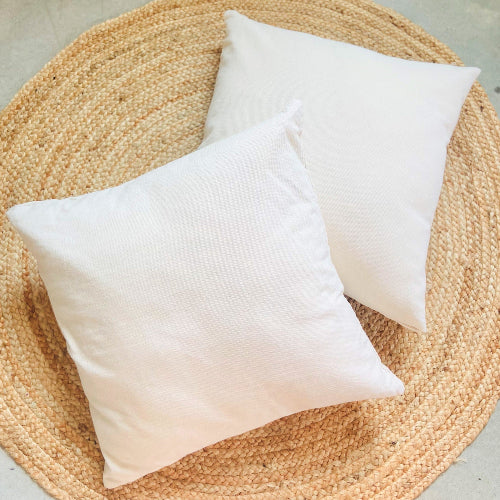 Two white pillows on a woven mat