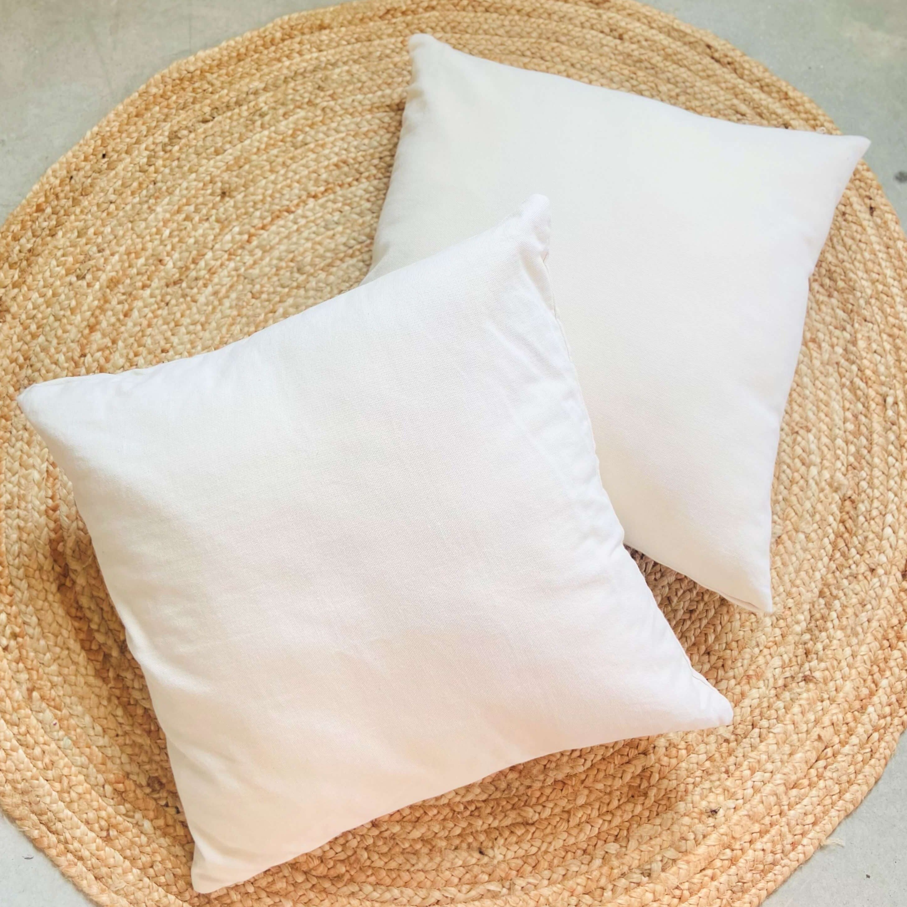 Two white pillows on a woven mat