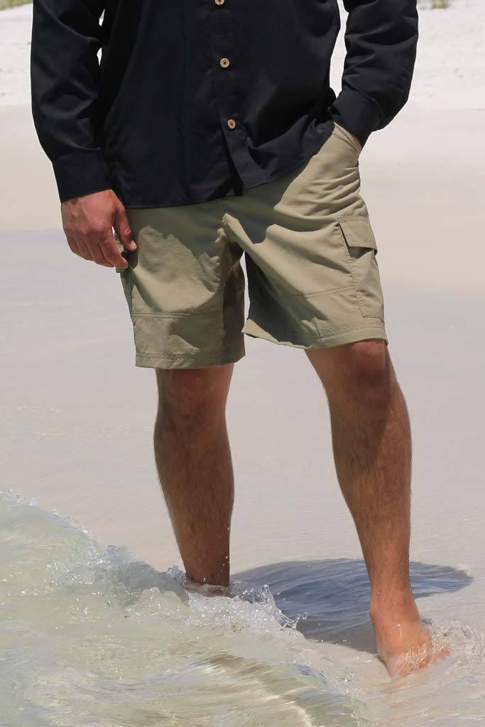 Person wearing green shorts and a dark shirt standing in shallow water.