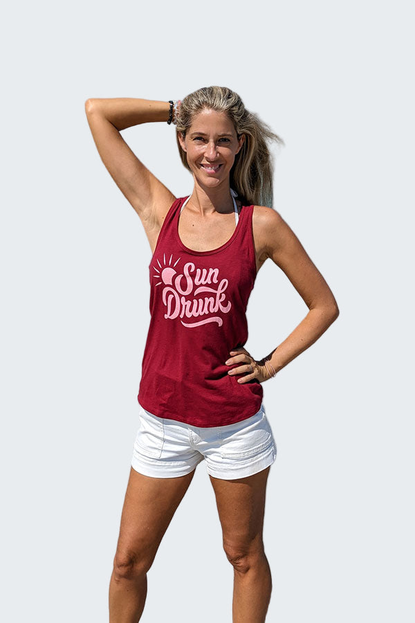Woman wearing a red tank top with 'Sun Drunk' text on a beach