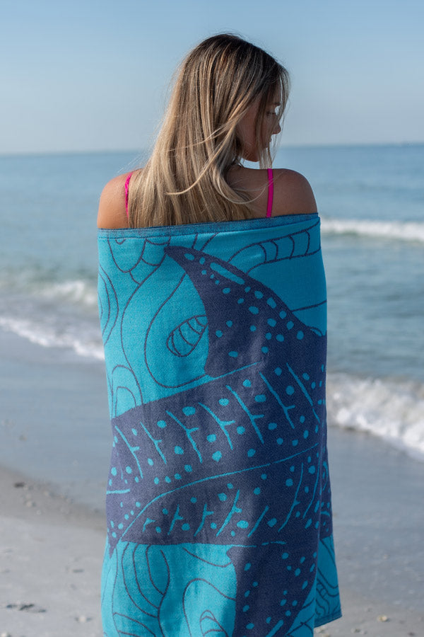 Woman wrapped in a blue and purple patterned towel on a beach