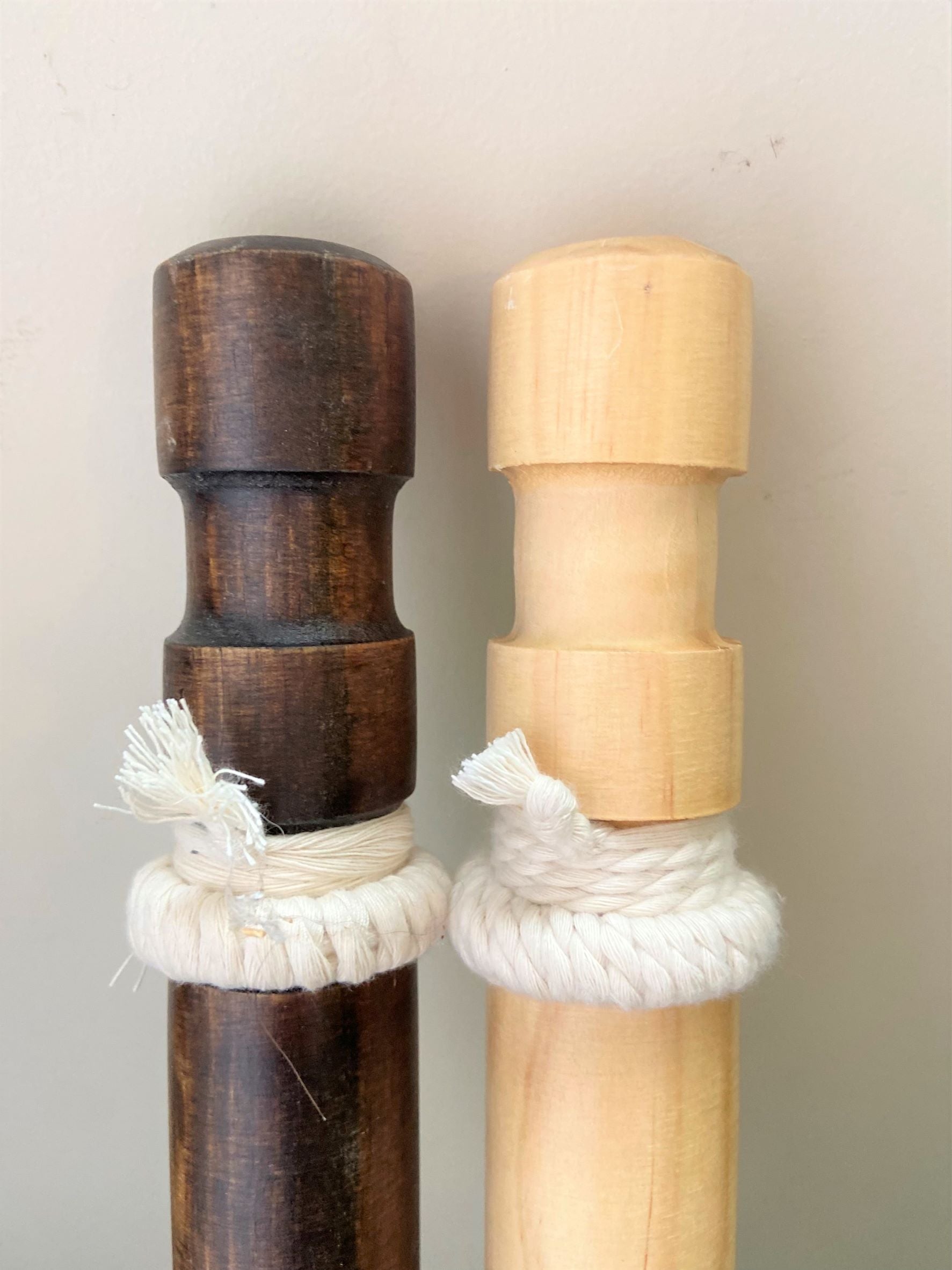Two wooden sticks with rope wrapping on a plain background
