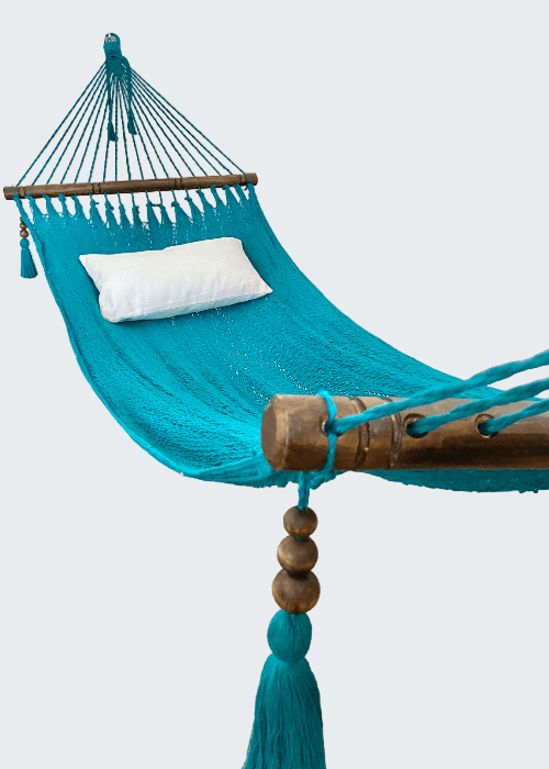 Turquoise hammock with wooden posts and tassels in a room setting.