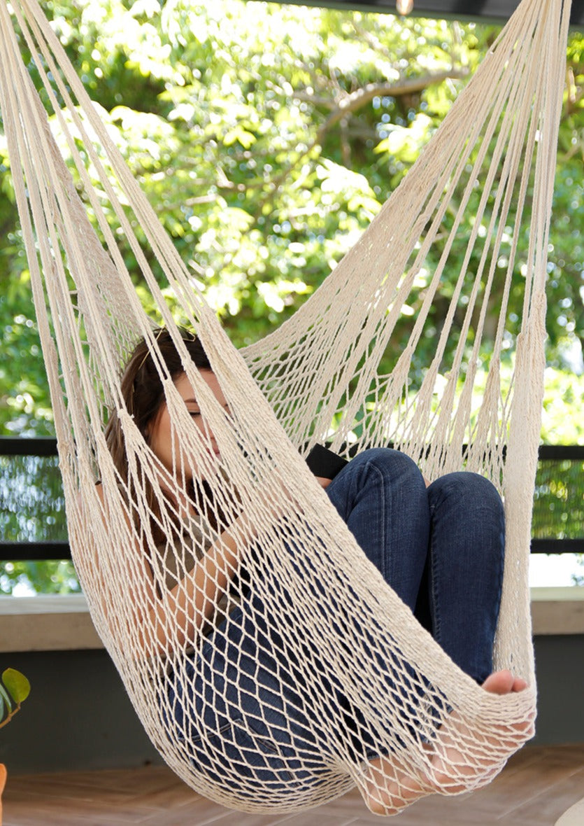 Person relaxing in a beige hammock with greenery in the background
