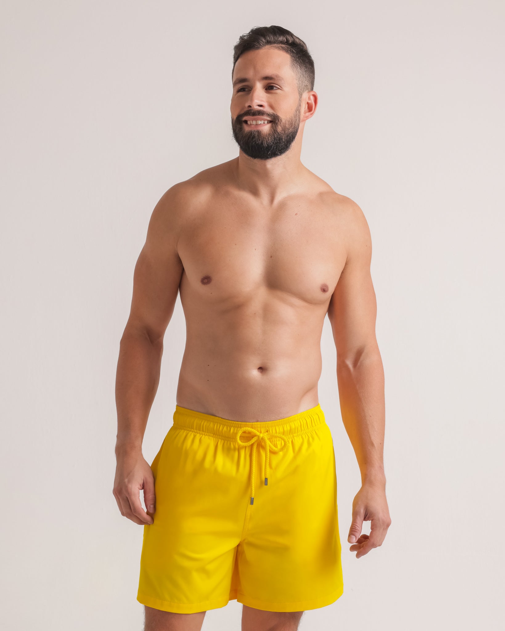 Man wearing yellow swim shorts against a plain background