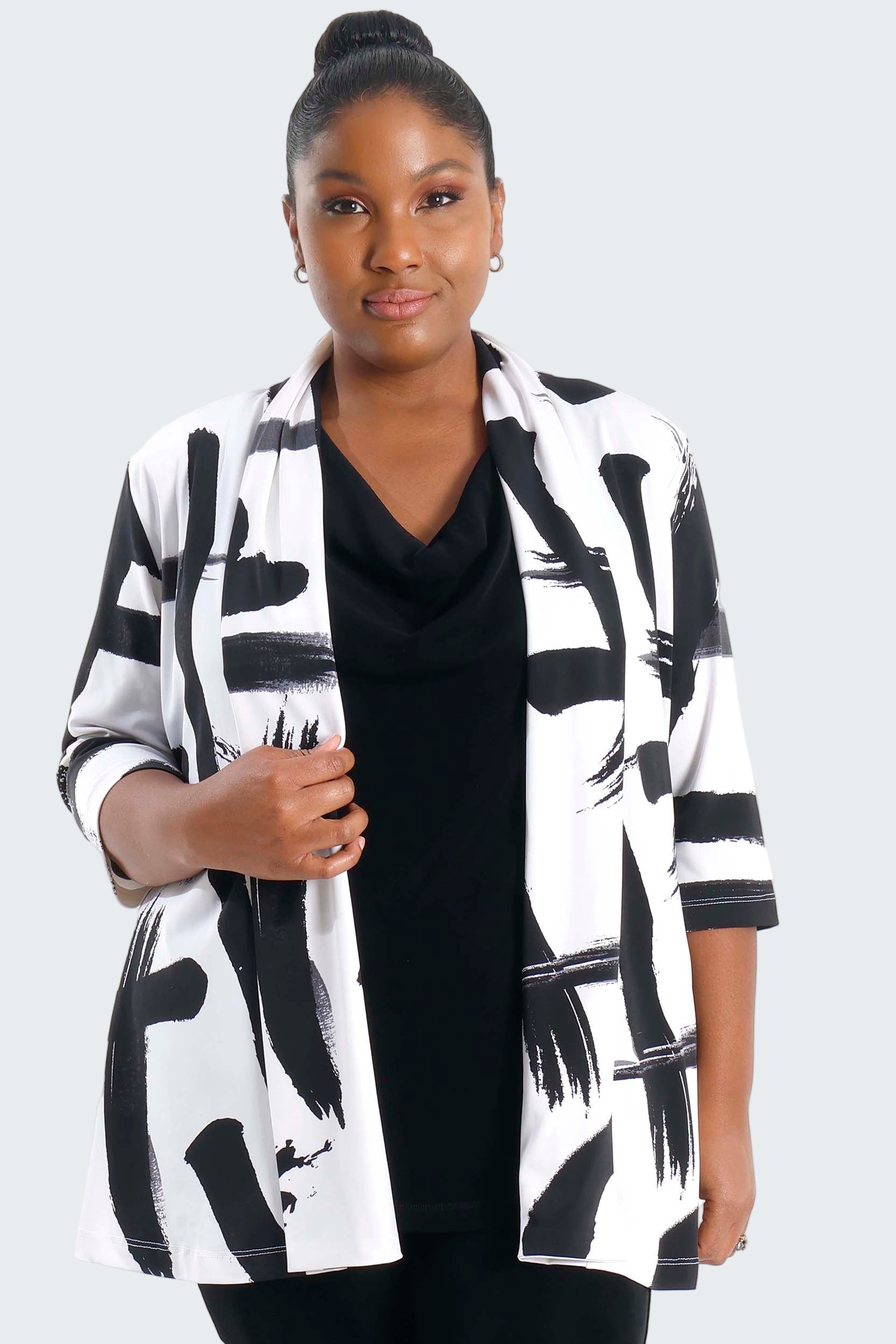 Woman wearing a black and white patterned cardigan over a black top on a white background