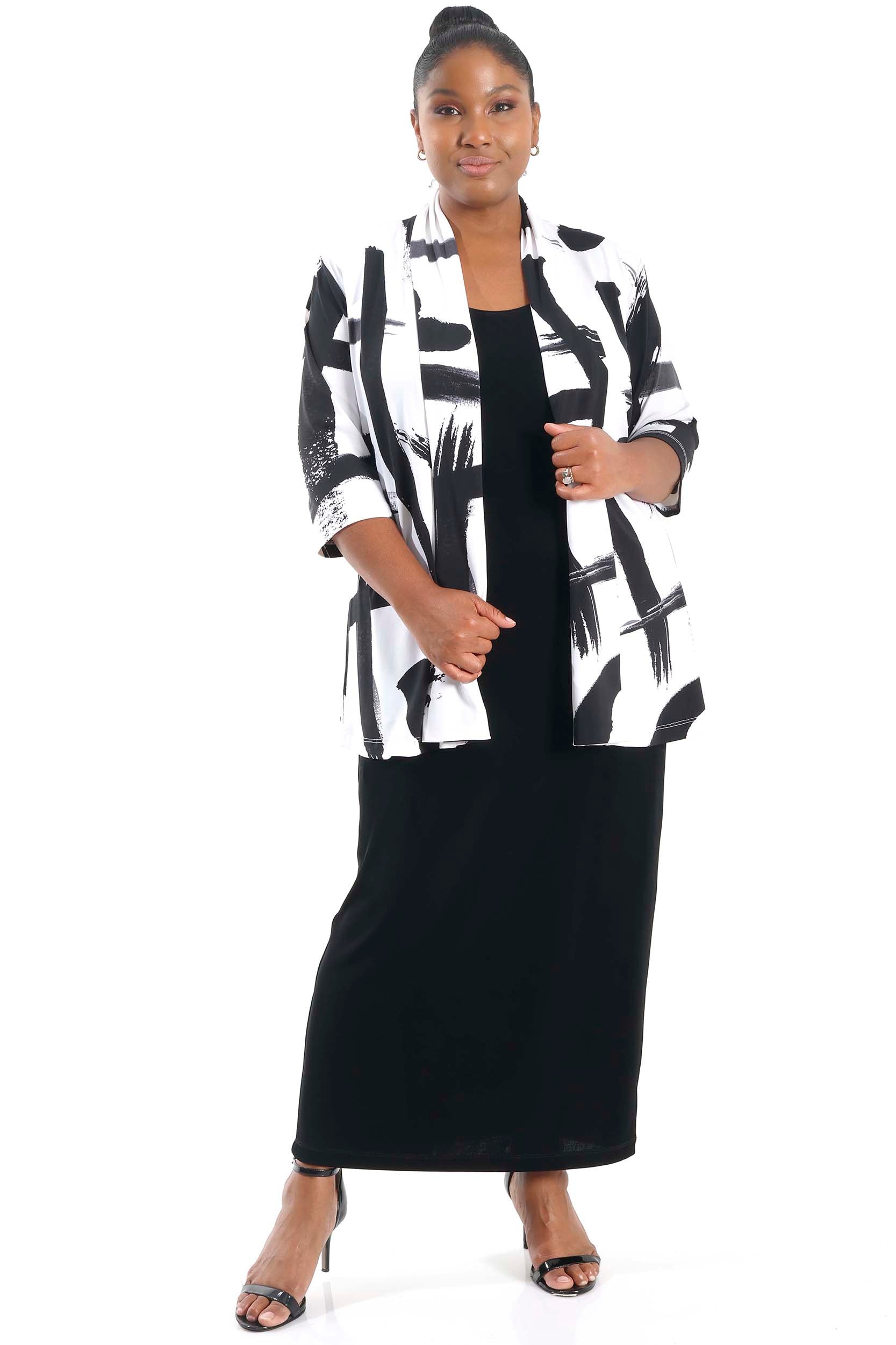 Woman wearing a black and white patterned jacket over a black dress on a white background