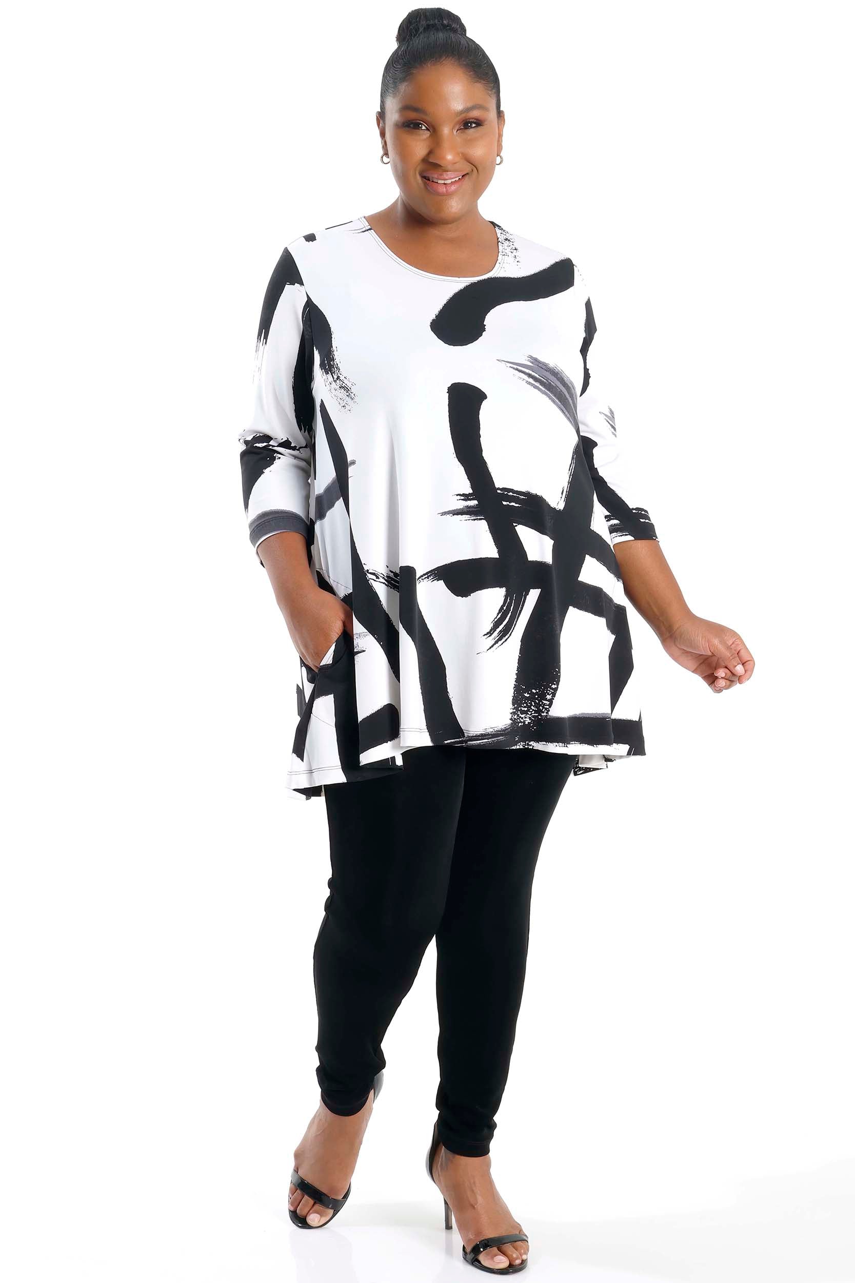 Person wearing a black and white abstract patterned top with black pants on a white background